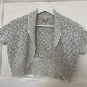 Kortärmad ljusgrå stickad bolerotopp från Arcade  - Jätte fin bolero som är  grå med silver detaljer  i stl M men mer åt S hållet, säljer för det inte kommer till användning längre 😢🩷🩷