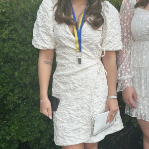 Student klänning - Säljer en superfin kort omlottklänning med puffärmar och v-ringning. Klänningen har snygg knytning i sidan och ett quiltat, blommigt mönster i tyget. Använd en gång på student, inga fläckar ser ut som ny! Perfekt för student eller sommaren ☀️NYPRIS ÄR 900kr