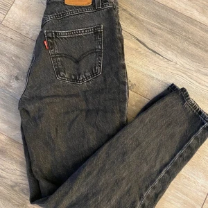 Levi's svarta mom jeans 80s Premium - Svarta Levi's Premium 80s Mom Jeans med hög midja och raka ben. Jeansen har en vintage vibe med tydliga sömmar och läderpatch bak i midjan. Tillverkade i kraftigt jeanstyg som ger en snygg och avslappnad look. Nypris 1250kr