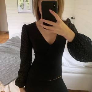 Svart omlottblus med spetsärmar Anna Field - Supersnygg svart omlottblus från Anna Field med v-ringning och långa, transparenta spetsärmar med diskret mönster. Figurnära passform och lätt stretchigt material i kroppen. Perfekt för dig som gillar unika detaljer. Säljer då den ibte kommer till användning! 💋om du undrar över något så fråga bara. 