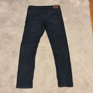 Mörkblå jeans från Lee i storlek 32/32 - Riktigt snygga jeans från Lee i storlek 32/32, dom är i riktigt bra skick. Modellen på jeansen heter Daren zip fly