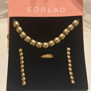 Guldfärgat smyckesset från Edblad - ✨Snyggt guldfärgat smyckesset från Edblad med armband, örhängen och ring. Armbandet, örhängena och ringen har fyrkantiga, mjukt rundade länkar som ger en modern och cool look, perfekt för dig som gillar statement-smycken med unik design✨