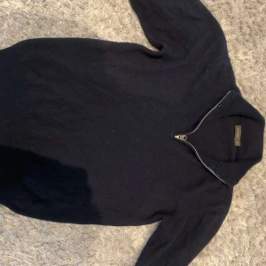 Oscar Jacobson tröja - Mörkblå kashmir  tröja från Oscar Jacobson med halv dragkedja vid kragen. Tröjan har lång ärm och ribbade muddar vid ärmslut och nederkant. Perfekt för lager-på-lager och snygg till jeans eller chinos.