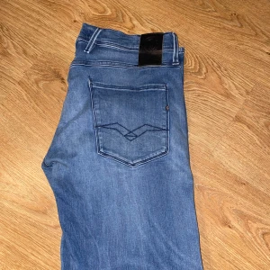 Replay Anbass jeans blå herr 33 - Säljer ett par snygga Replay jeans i klassisk blå denim. Modellen har perfekt passform med stretch som gör dem både bekväma och stiliga – funkar lika bra till vardags som till en kväll ute!  👖 Detaljer: 	•	Märke: Replay 	•	Färg: Mellanblå / lätt tvättad 	•	Storlek: (fyll i din storlek här) 	•	Passform: Slim / Regular (ange rätt) 	•	Kvalitet: Mycket bra skick, sparsamt använda 	•	Snygga detaljer på bakfickan och diskret Replay-logga fram