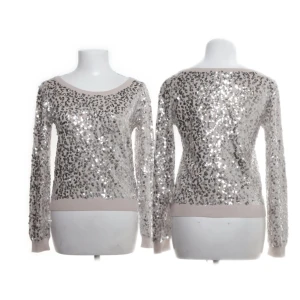 Glittrig paljett-tröja från H&M XS - Supersnygg ljusbeige tröja från H&M i storlek XS, täckt med silvriga paljetter som ger ett riktigt glittrigt intryck. Tröjan har rund halsringning och långa ärmar, perfekt när du vill sticka ut lite extra.