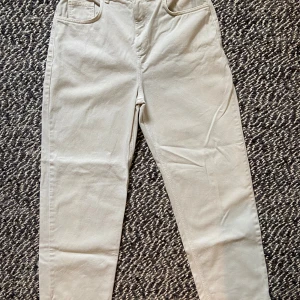 Beiga raka jeans från RV, W32 - Snygga beiga jeans från RV (Reclaimer Vintage) i rak modell med klassiska fem fickor och bälteshällor. Tillverkade i bomullstyg med en stilren look och diskret RV-läderpatch bak. Perfekta för dig som gillar enkel och clean stil. Endast använda 2 gånger men har tyvärr en liten fläck på ena benet (syns knappt!) Köpta till en kille men passar även tjej!