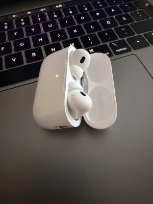AirPods Pro 2 - Apple AirPods Pro med laddningsetui. Trådlösa hörlurar med aktiv brusreducering och transparensläge. Skick: mycket bra, endast mindre ytliga repor på etuiet. Perfekt för musik, samtal och träning. Levereras med originaletui.