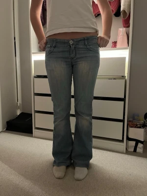 Lågmidjade ljusblå bootcut jeans - Säljer ett par lågmidjade ljusblå jeans från puzzle med bootcut passform. Jeansen har slitningar framtill, broderade bakfickor och klassisk knappstängning. Hör av dig för frågor! Pris kan diskuteras!