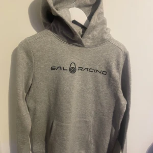 Sail racing huddie - En grå sailracing huddie säljs. Den är knappt använd och är i jättebra skick. Storlek=176