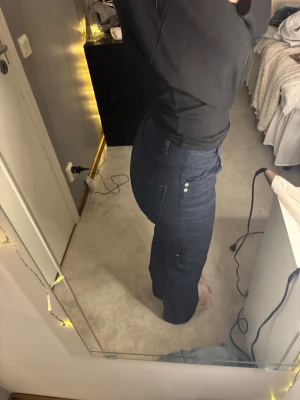 Mörkblå bootcut jeans från Alba Moda - Snygga mörkblå jeans från Alba Moda med klassisk rak passform och medel-hög midja. Jeansen har silverfärgade knappar och detaljer, samt stora fickor bak. Materialet är jeans och de sitter riktigt bra på kroppen.