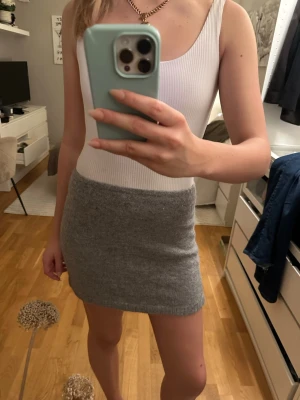 Grå stickad kortkjol Gina Tricot - Supermysig grå stickad kortkjol från Gina Tricot i storlek S. Kjolen har en enkel och stilren design med ribbad kant nedtill. Perfekt att matcha med en snygg topp eller hoodie för en chill look.