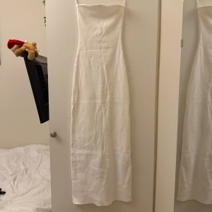 Vit bandeauklänning med slits - Superfin vit bandeauklänning med slits. Klänningen är figurnära och har en snygg slits baktill.