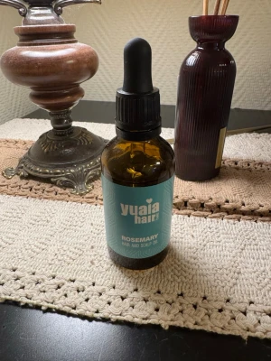 Yuaia Hair Rosemary Oil - Använd ett par gånger. En brun glasflaska med pipett fylld med Yuaia Hair Rosemary Hair and Scalp Oil. Oljan är framtagen för hår och hårbotten och kommer i en snygg turkos etikett. Perfekt för dig som vill boosta håret med rosmarinextrakt.