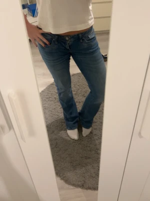 Blå bootcut jeans från LTB - Säljer ett par klassiska blå LTB jeans med bootcut och låg midja. Jeansen har fem fickor, knapp och dragkedja framtill. Perfekta till sneakers eller boots och gjorda i mjukt jeansmaterial. Jeansen är i storlek W27/34L. Jeansen har inga större tecken på användning men är lite slitna precis vid slutet av jeansen 