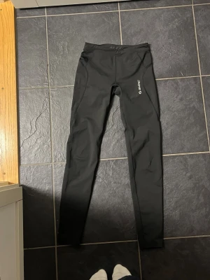 Svarta träningsleggings från SOC - Svarta leggings från SOC med smal passform och hög midja. Tillverkade i stretchigt syntetmaterial som andas, med meshdetaljer vid höfterna. Perfekta för träning och har en stilren look med logga på benet.