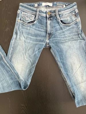 Replay ljusblå jeans med raka ben - Säljer ett par ljusblå jeans från Replay med klassisk femficksdesign. Jeansen har raka ben och normal passform, med Replay-lapp bak i midjan. Perfekta till sneakers eller boots för en avslappnad look.
