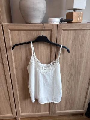 Vit spetsdetaljerad topp - Säljer en vit linnetopp från Shein i storlek XS. Toppen har tunna axelband och vacker spets! 
