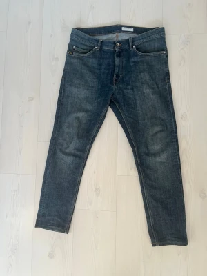 Tiger of Sweden Evolve jeans blå 34/34 - Snygga blå jeans från Tiger of Sweden, modell Evolve. Klassisk femficksdesign med raka ben och normal passform. Jeansen har en mörk tvätt med subtila slitningar och är tillverkade i bomullsmaterial. Perfekta för dig som gillar stilrena och tidlösa jeans.