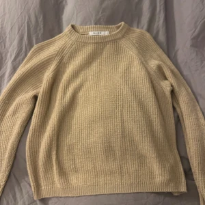 Beige stickad tröja från NA-KD - Säljer en beige stickad tröja från NA-KD i storlek S. Tröjan har en rund halsringning och ribbad struktur som ger en chill och enkel vibe. Perfekt att slänga på sig när det är lite kyligt ute. Långärmad och loose fit för extra komfort.