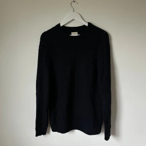 Mörkblå stickad tröja Selected Homme - Mörkblå stickad tröja från Selected Homme i storlek L. Tröjan har ett snyggt fiskbensmönster och rund hals. Materialet är en mix av ull, nylon och akryl som gör den både mjuk och varm. Perfekt för dig som gillar stilrena och klassiska plagg. 4B1