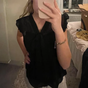 Svart blus med knyt - Snygg svart blus med knyt framtill och korta ärmar.