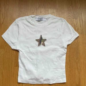 Vit topp med camo-stjärna  - Vit  topp och magtröja från Primark i storlek XS med en cool stjärnapplikation i camouflage-tyg på bröstet💕