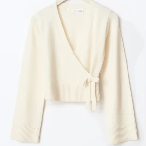  omlottkofta från Gina Tricot - Superfin beige omlottkofta från Gina Tricot med knyt i sidan och breda ribbade muddar. Vida muddar! Storlek 170