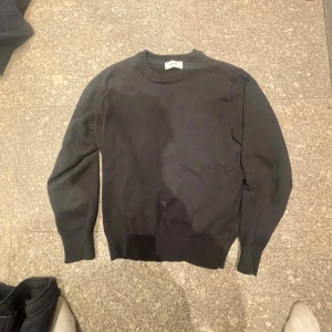  Knitt, Les Deux knitt - Svart stickad tröja från Les Deux med rund hals och ribbade muddar vid ärmslut och nederkant. Enkel och stilren design som funkar till många olika looks. Perfekt för dig som gillar klassiska plagg med en modern touch.