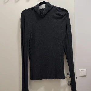 Mörkgrå polotröja från H&M, storlek S - Säljer en stilren mörkgrå hoodie från H&M i storlek S. Tröjan har lång ärm och huva, tillverkad i mjukt och tunt material som känns skönt mot huden. Perfekt för chill dagar och enkel att matcha med jeans eller joggers.