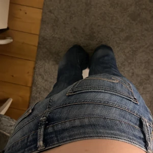 Blå bootcut jeans med slits - Säljer ett par blå jeans med bootcut passform och slits längs utsidan av benen. Det var skinny men som är omsydda till bootcut och slits vid högra knät. Nakdelen med jeansen är hålet på bild 3. Men de är inget som syns när dom sitter på. Också jätte enkelt att fixa och sy igen. 