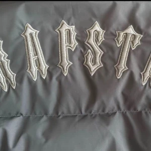  Trapstar jacka  - Säljer en svart pufferjacka från Trapstar med stor broderad logga på ryggen och rund logotyp på bröstet. Jackan har huva, dragkedja framtill och två sidofickor. Perfekt för kalla dagar och har en clean streetwear-vibe.