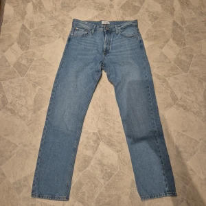 Blå jeans från Jack & Jones, storlek 32/34 - Snygga klassiska blå jeans från Jack & Jones i regular modell. Jeansen har fem fickor, knappgylf och bälteshällor. Passar dig som gillar en tidlös look med straight fit.