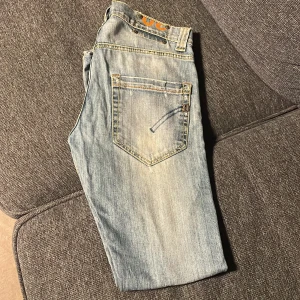 Dondup jeans - Snygga ljusblå jeans från dondup med klassisk femficksdesign och knappgylf. Jeansen har slitna detaljer och kontrastsömmar, samt dondup-logga på bakfickan. Perfekt för dig som gillar en avslappnad och cool stil. Pris kan diskuteras. Skick 5/10, ett litet hål vid gylfen som man inte ser vid användning.