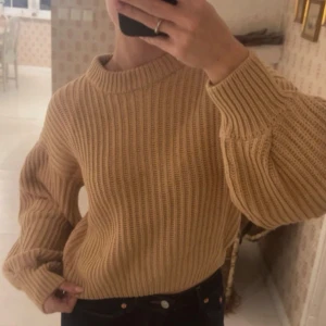 Beige ribbad stickad tröja - Säljer en beige stickad tröja med ribbad struktur och rund hals. Tröjan är lite kortare i modellen och har ballong ärmar. Aldrig använd🤎