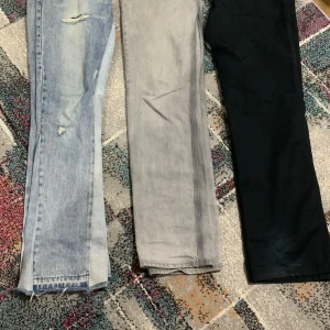 Två par raka jeans i blått och grått - Säljer två par raka jeans, ett i ljusblå denim med slitningar och ett i grått. Båda har klassisk femficksdesign och normal passform. Perfekta för en avslappnad och trendig look.