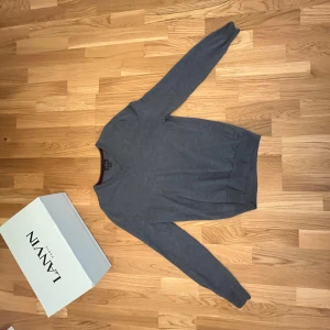 Grå/ baby blå merinoulltröja Brooks Brothers - Snygg grå tröja från Brooks Brothers i extra fin merinoull. Klassisk v-ringad modell med lång ärm och ribbade muddar vid ärmslut och nederkant. Perfekt för dig som gillar stilrena och tidlösa plagg med skön passform.