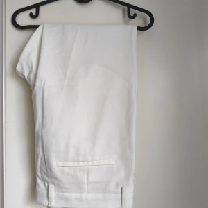 Vita dresade byxor från Zara - Snygga vita dressade byxor från Zara i klassisk rak modell. Byxorna har pressveck, diskreta bakfickor och är tillverkade i ett mjukt bomullsmaterial. Perfekta för en clean och stilren look. Byxorna är som nya.