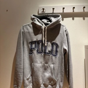 Grå hoodie från Polo Ralph Lauren - Snygg grå hoodie från Polo Ralph Lauren med stor POLO-logga i mörkblått på bröstet, klassisk huva med snörning och ficka. Har broderad logga och en cool etikett med '67'. Perfekt för chill dagar. Passar xs/s. Skicka gärna prisförslag 