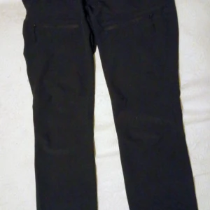 Svarta byxor med dragkedjor Fritidsbyxa - Svarta byxor med raka ben och praktiska dragkedjor vid fickorna. Snygg och enkel design som passar till många olika stilar. Materialet känns mjukt och bekvämt, perfekt för dig som gillar en clean look.