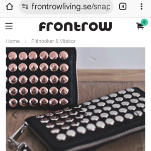 Frontrow Living/Nyskick!! - Cool svart plånbok /clutch väska  i skinn med stora, blanka nitar i metallic på framsidan. Plånboken har dragkedja runtom och avtagbar handledsrem. Insidan har flera kortfack och ett myntfack med dragkedja. Perfekt för dig som gillar en edgy stil.Märket är Frontrow Living. I nyskick! Endast använd fåtal ggr. Nypris 999 kr. 