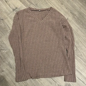 Brun ribbad långärmad tröja - Säljer en brun ribbad tröja med v-ringad hals och långa ärmar. Tröjan har en loose passform och är perfekt för dig som gillar en chill och enkel stil. Materialet känns mjukt och skönt mot huden, och den ribbade strukturen ger en snygg touch.