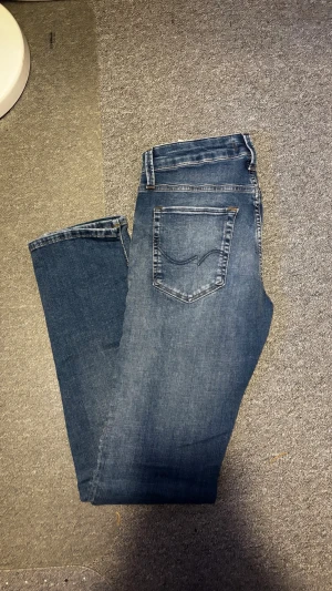 Blå slim fit jeans från Jack & Jones - Snygga blå jeans från Jack & Jones i modellen Slim/Glenn. Jeansen har klassisk femficksdesign, normal midja och smal passform. Tillverkade i mjukt denimtyg som ger en bekväm känsla och stilren look.