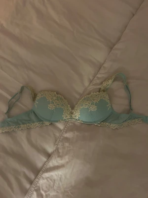 Intimissimi bh  - Snygg ljusblå bh med vadderade kupor och dekorativa spetsdetaljer i vit med blommönster. Justerbara axelband och klassisk knäppning bak. Aldrig använts. Storlek 75C ev 75B då jag har tyvärr klippt av lappen och kommer inte ihåg vilken storlek. 