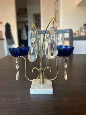 Kandelaber med blå detaljer och prismor - Kandelaber med plats för två ljus. Den har blå blommor och hängande prismor. Foten är gjord av marmor. Behöver putsas