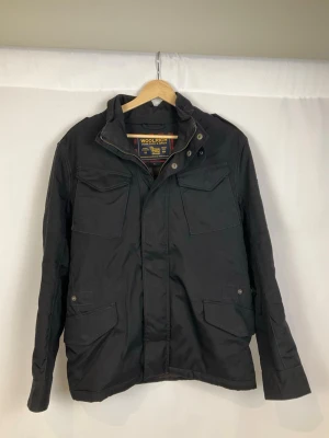 Woolrich Jacka  - Tja säljer en snygg svart jacka från Woolrich med krage och detaljer som dragkedjor och knappar framtill. Jackan är i väldigt fint skick och säljs för endast 1399kr. Nypris över 6000kr. Skriv vid frågor eller ifall du vill ha fler bilder. Storlek Small.