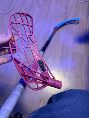 Innebandyblad i rosa plast - Säljer ett rosa innebandyblad med coolt rutmönster och svart detalj. Bladet är gjort i plast och har en böjd form som passar för snabba skott och passningar. Perfekt för dig som vill byta ut eller uppgradera bladet på din klubba.