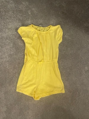 Gul jumpsuit med kort ärm. Barnstorlek 160!! - Snygg gul jumpsuit med korta ärmar och resår i midjan. Skriv för mer exakta mått! Jättebra skick nästan aldrig använt. Perfekt på sommaren 
