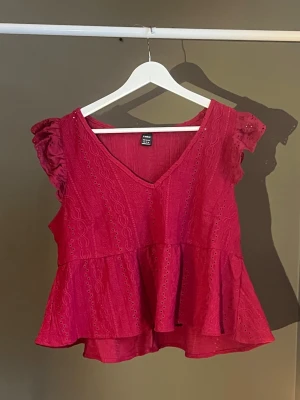 Röd volangblus med spetsdetaljer - Söt röd blus med v-ringning, volangkant nedtill och broderade spetsdetaljer. Ärmlös modell med volang vid axlarna och luftig passform. Perfekt för dig som vill ha en feminin och trendig topp till sommaren. Köpt från SHEIN, använts några gånger 🌹