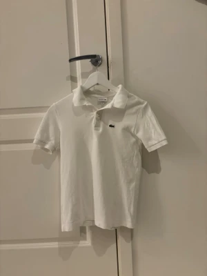 Vit Lacoste piké - Tjena. Säljer denna vita Lacoste pikén i storlek 164. Den har inga defekter eller fläckar. Använd cirka 8 gånger.