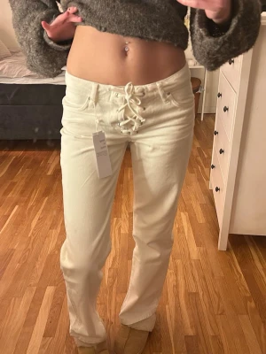 Lacing jeans Gina Tricot  - Säljer ett par vita jeans från Perfect Jeans med unik snörning. Storleken är liten i och med att jeansen passar mig som vanligtvis har strl 34/36 i byxor. Modellen har raka ben och klassisk femficksdesign. Materialet är mjukt och stretchigt, vilket gör dem riktigt bekväma. Perfekta för dig som vill sticka ut lite extra!